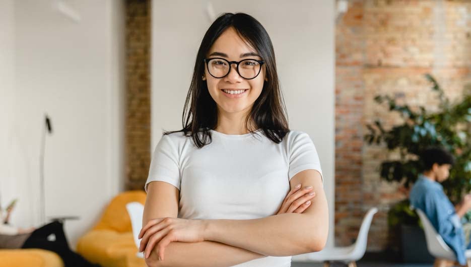 Successful young asian businesswoman with arms crossed in office
